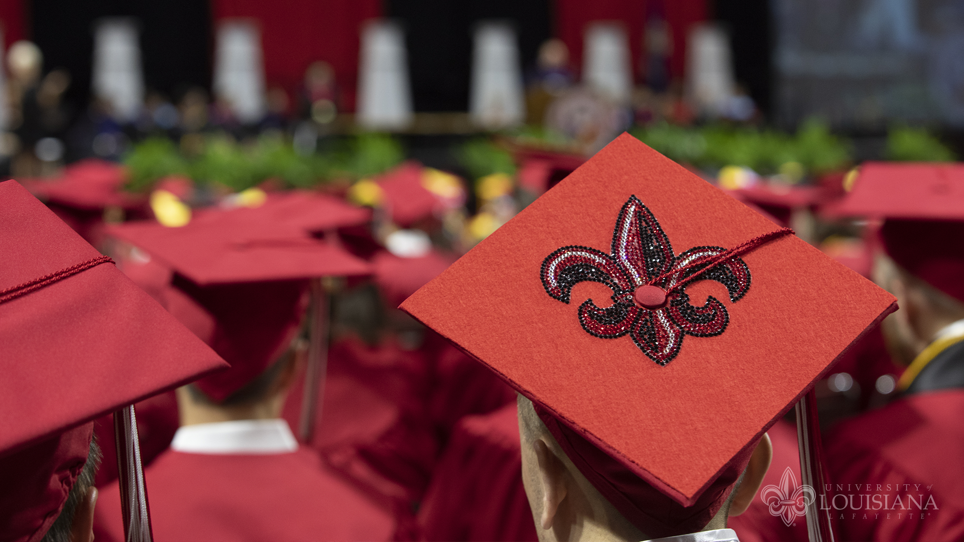 Photo of the back of a graduate's mortarboard with the UL Lafayette fleur-de-lis embellishment on it.